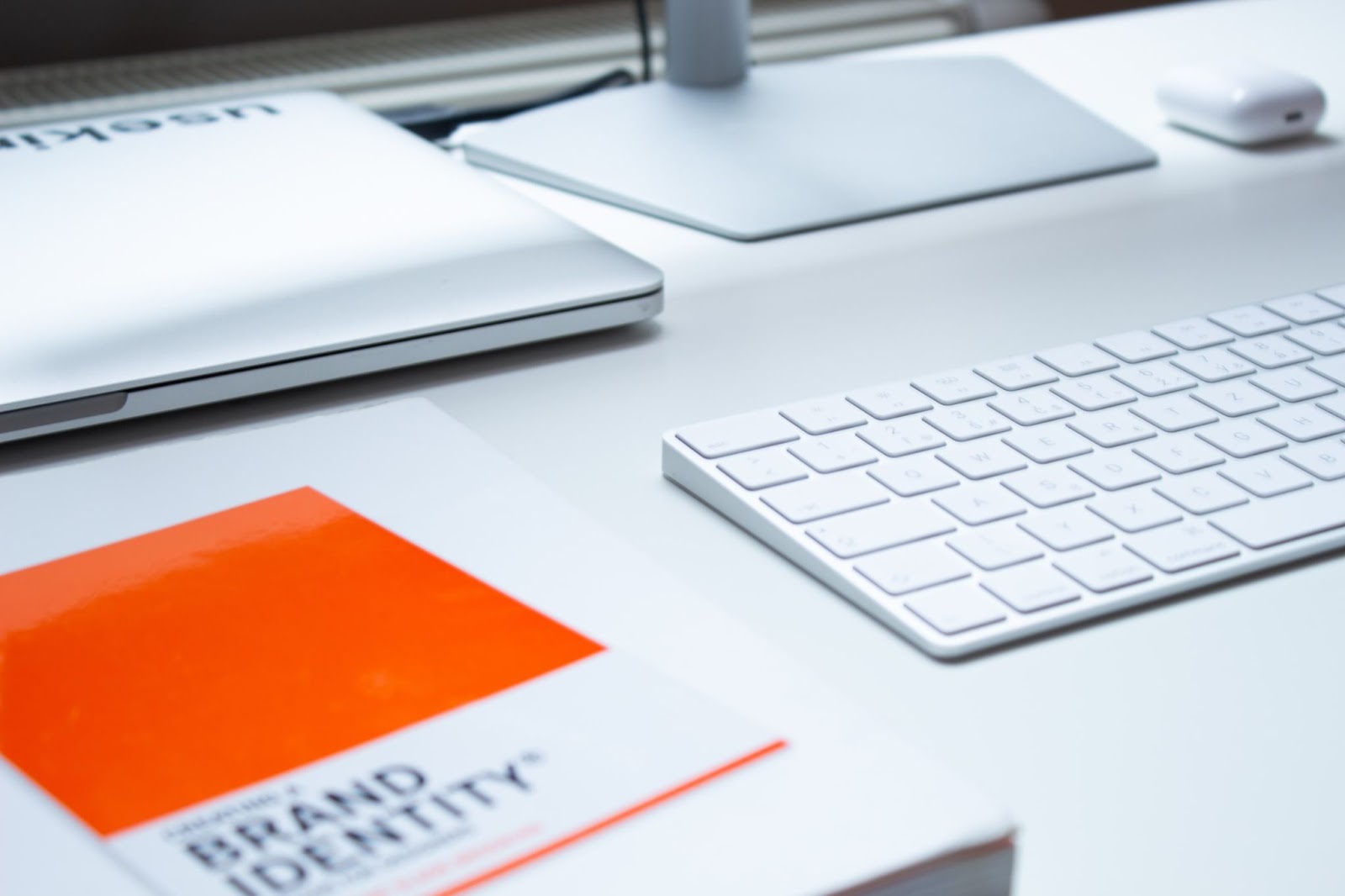 Table with peripheral, keyboard, laptop on desk displaying text: BRAND IDENTITY.