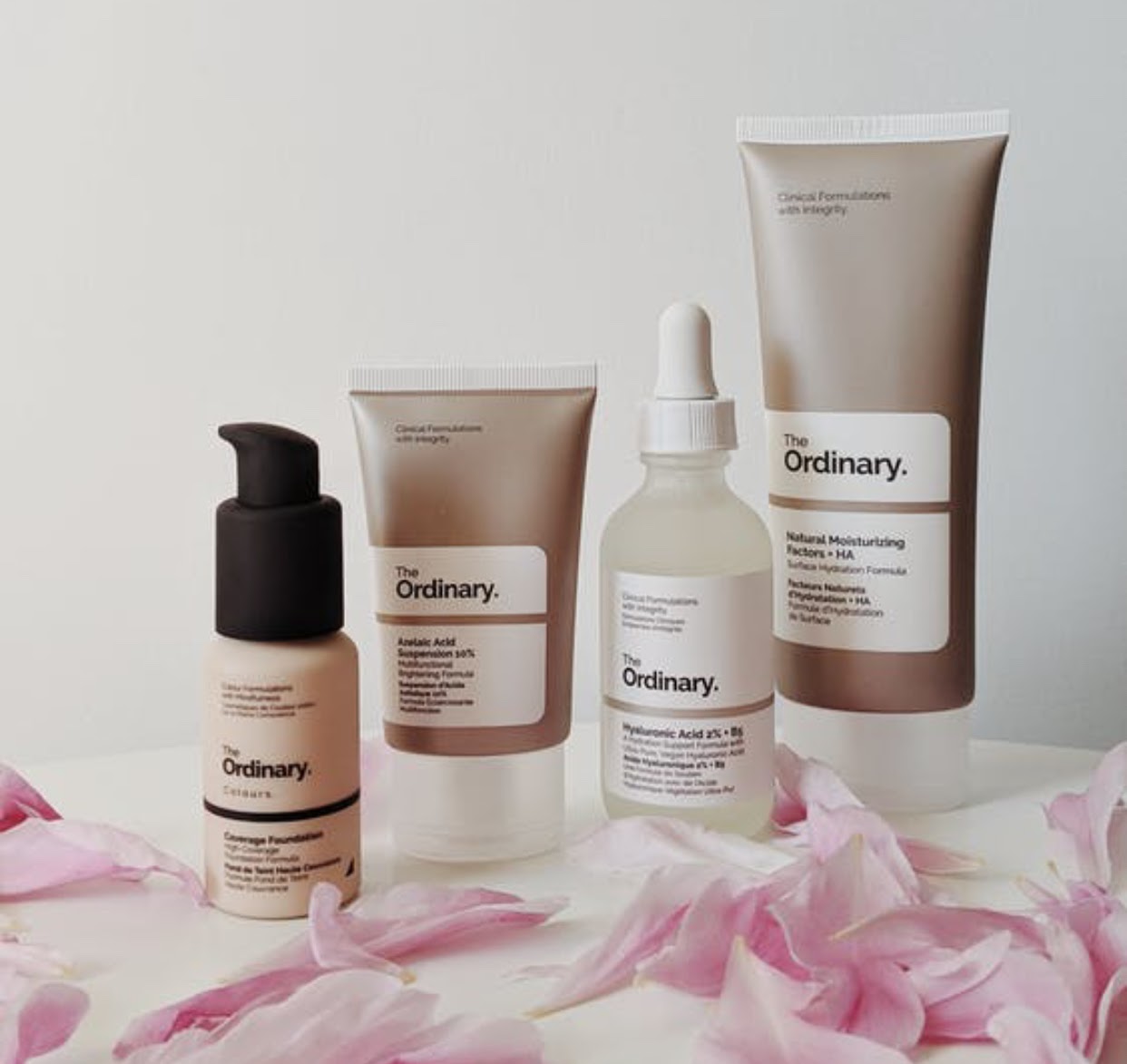 Liquid cosmetic products in bottles and tubes from The Ordinary brand, including Azelaic Acid Suspension 30%, Niacinamide 10% + Zinc 1%, and Hyaluronic Acid 2%.