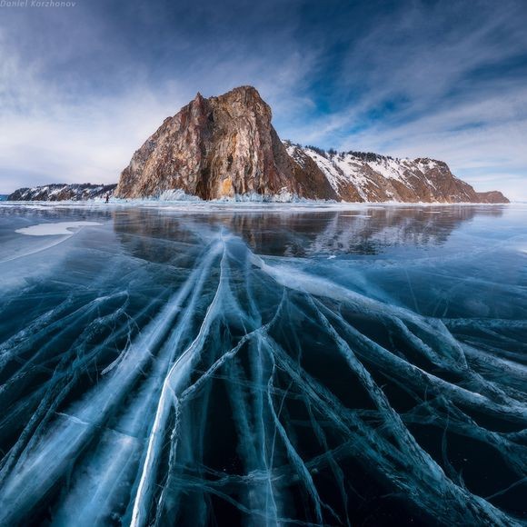 Lake Baikal with crystal clear blue water, fluffy clouds in the sky, and the text "Daniel Korzhonov" - a stunning natural landmark.