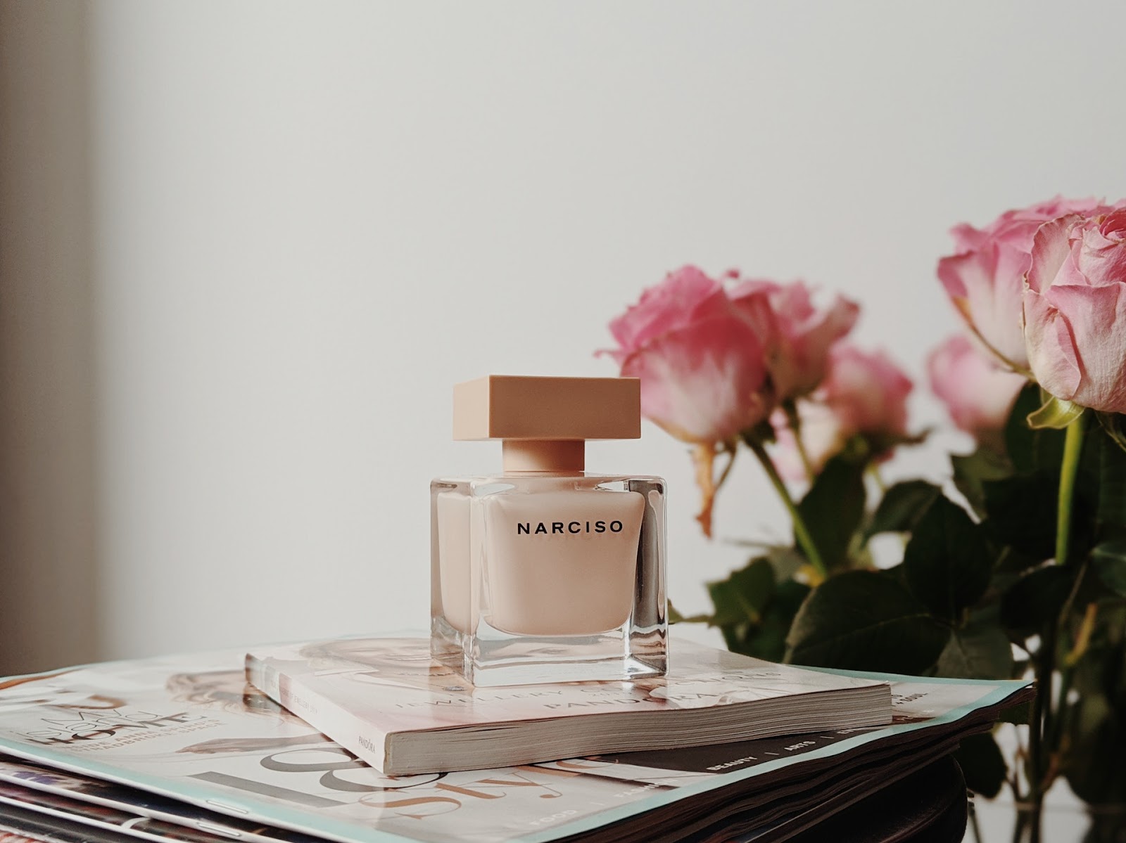 Artificial flower arrangement with office supplies, perfume bottles, and jarred goods, featuring a flower with text "PANDORA NARCISO".
