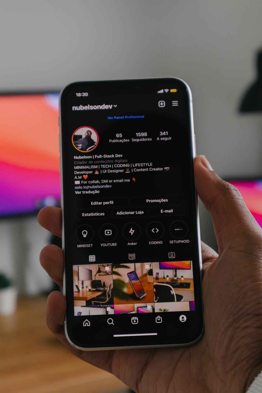 Hand holding mobile phone displaying Instagram profile with text "18:30 nubelsondev". Profile includes bio "Nubelson | Full-Stack Dev, MINIMALISM | TECH | CODING | LIFESTYLE, Developer UI Designer, For coll