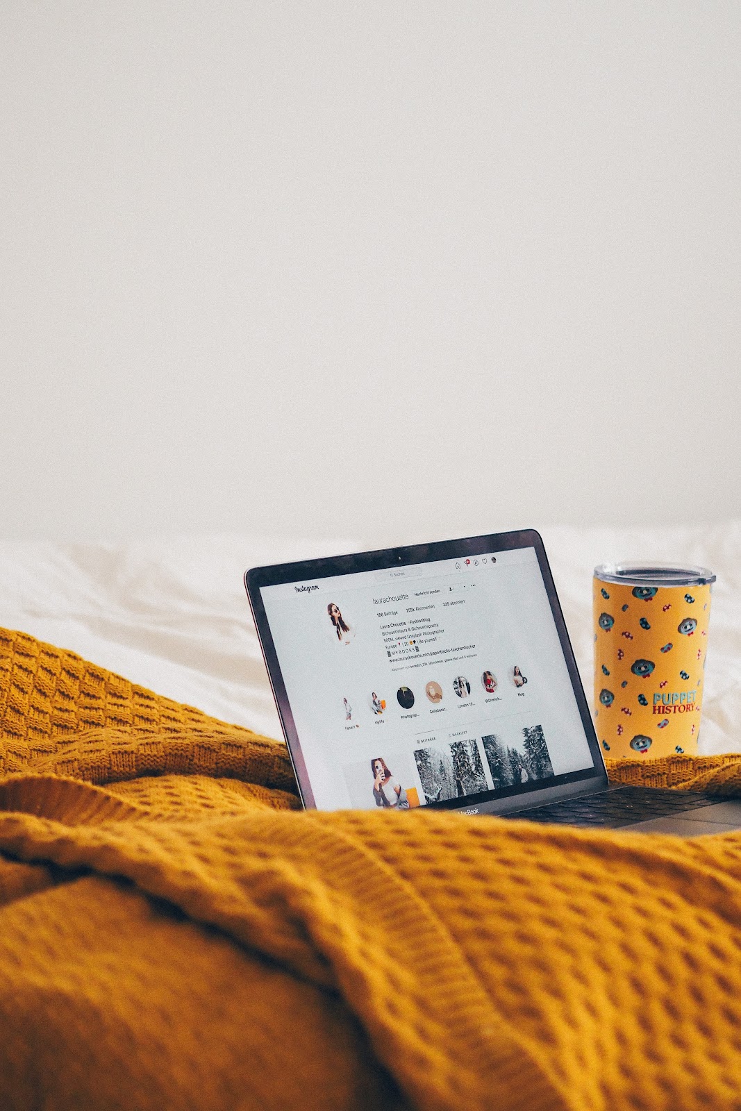 Instagram logo on a laptop screen with various text and rectangular drinkware on a wooden surface.