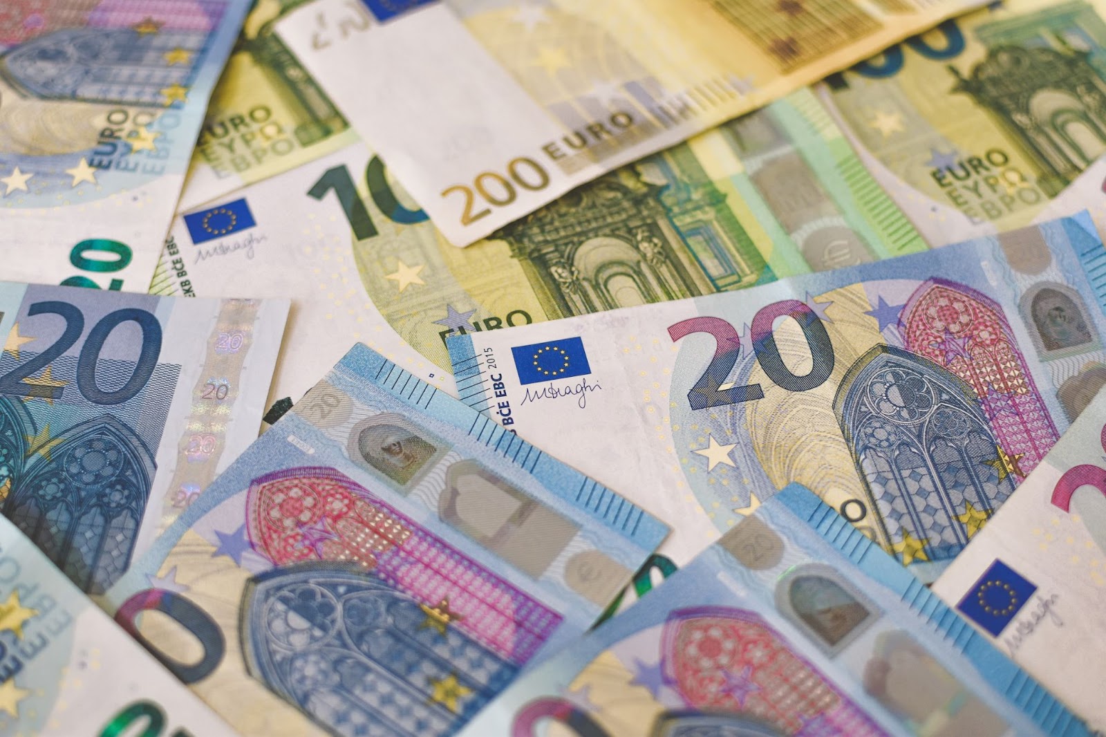 Euro banknotes of varying denominations arranged neatly with text showing 200 Euro, 100 Euro, and other currency symbols.