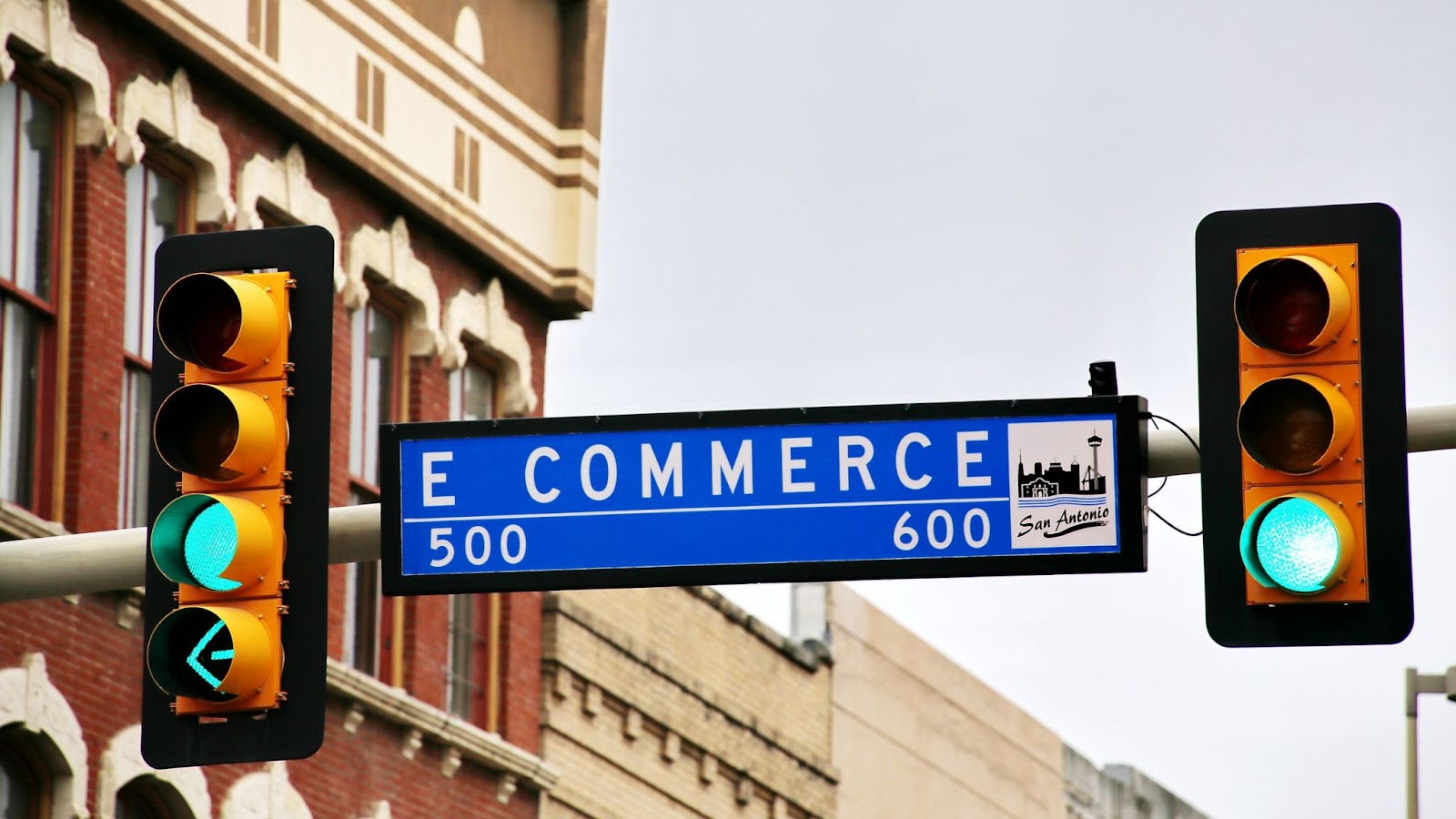 Traffic light, infrastructure silhouette against the sky, rectangle with "G E COMMERCE 500 600 San Antonio" text, building with G emblem.