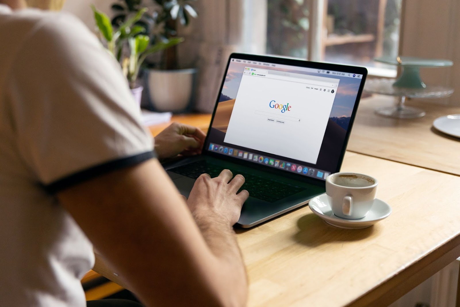 Two persons sitting at a table with laptops and coffee cups, one laptop displaying a text that reads "○○ Google".